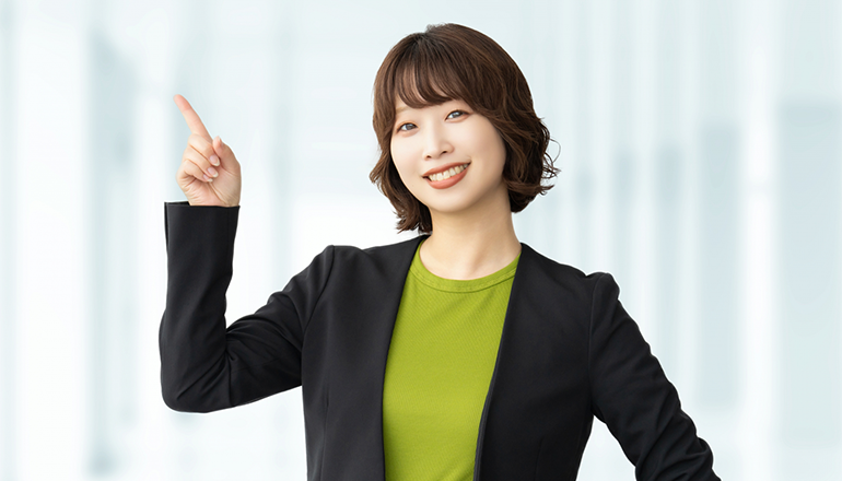 人差し指でハンドサインをするスーツを着た女性の画像